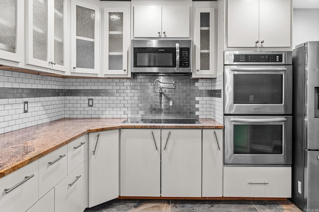 kitchen with white cabinets, light stone counters, stainless steel appliances, and decorative backsplash