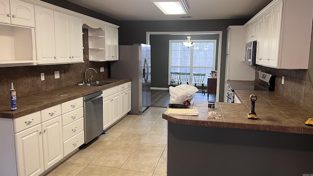 kitchen featuring light tile patterned flooring, white cabinets, stainless steel appliances, and a sink