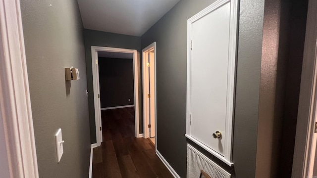 corridor featuring dark wood finished floors and baseboards