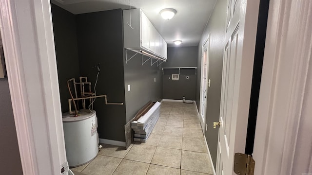 interior space with light tile patterned floors, baseboards, and water heater