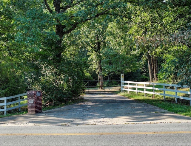 view of street featuring a wooded view and a gate