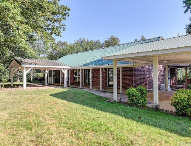 rear view of house featuring a lawn, brick siding, and metal roof
