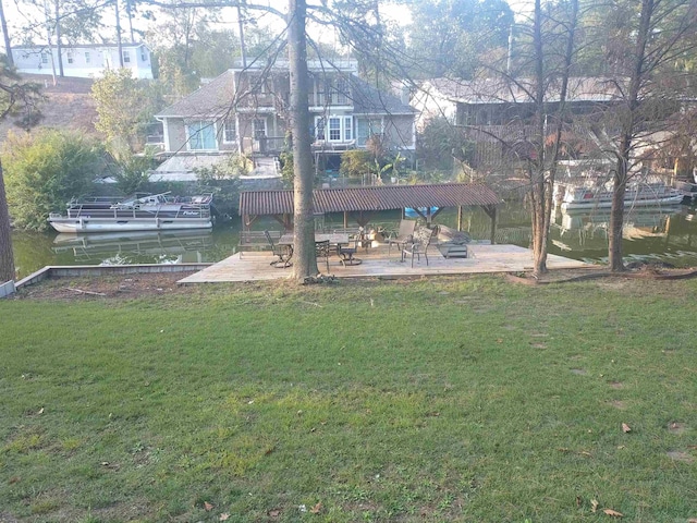 view of home's community with a patio, a yard, a water view, and a boat dock