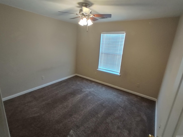 spare room with dark colored carpet and ceiling fan