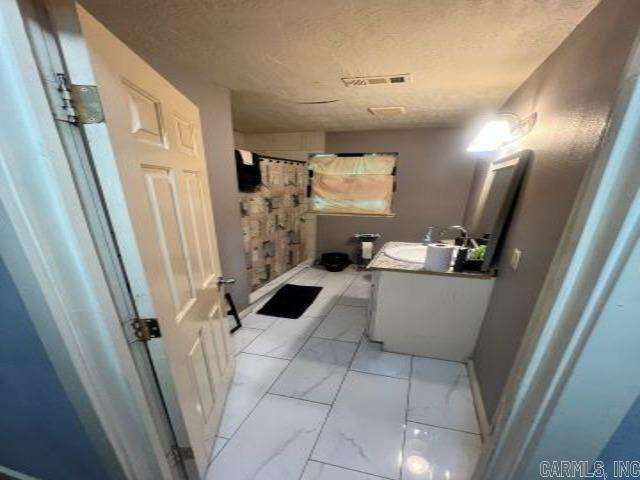 bathroom with walk in shower, a textured ceiling, and vanity