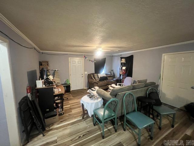 living room featuring crown molding, a textured ceiling, and hardwood / wood-style floors