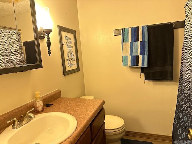 bathroom with a textured ceiling, vanity, and toilet