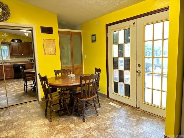 dining room featuring a wealth of natural light, sink, a textured ceiling, and french doors