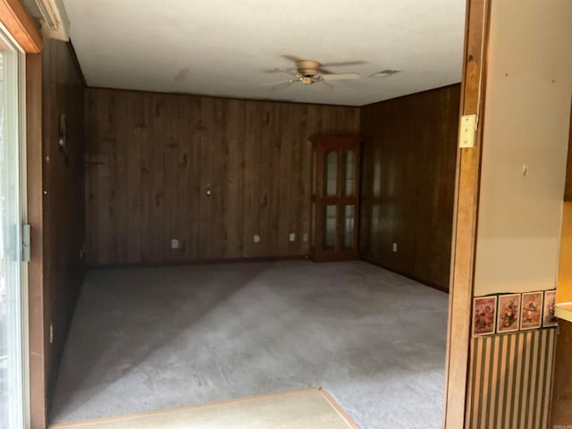 unfurnished room with ceiling fan and wooden walls