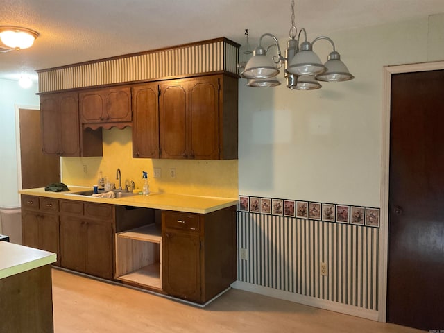 kitchen featuring a textured ceiling, an inviting chandelier, pendant lighting, light hardwood / wood-style floors, and sink