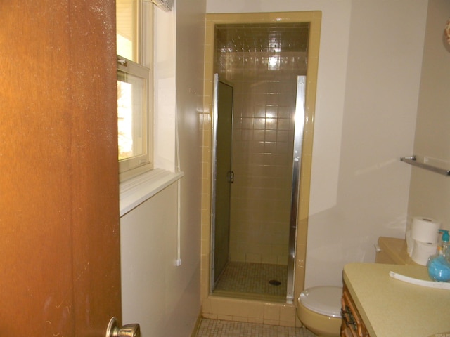 bathroom with a shower with door, vanity, toilet, and tile patterned flooring