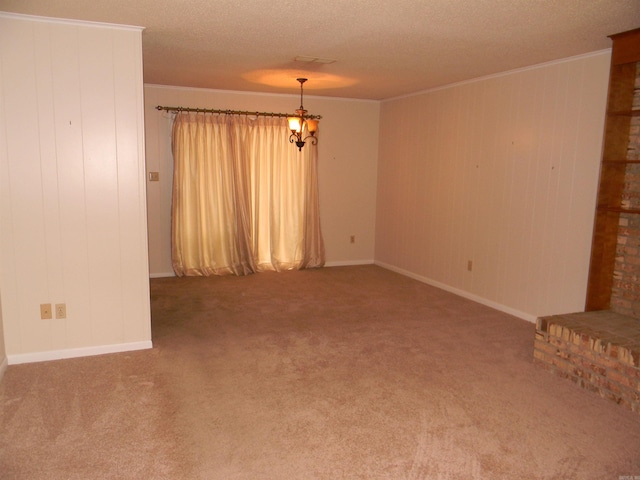 carpeted spare room featuring ornamental molding, a fireplace, a notable chandelier, and a textured ceiling