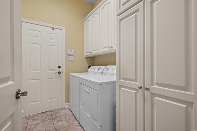 clothes washing area with washing machine and clothes dryer, cabinets, and light tile patterned floors