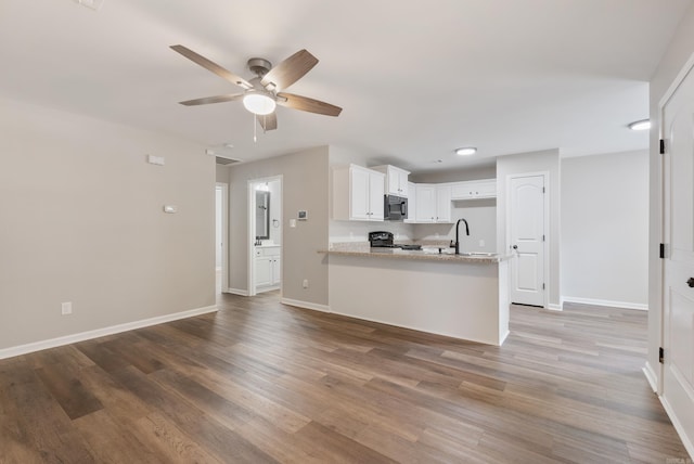 kitchen with hardwood / wood-style floors, black electric range, kitchen peninsula, ceiling fan, and white cabinets