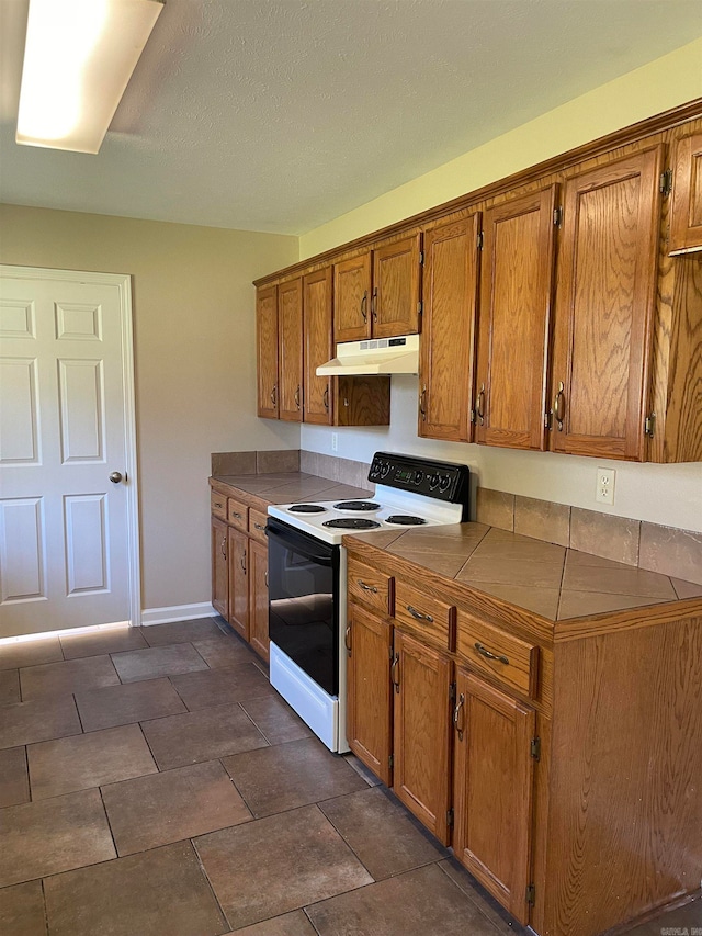 kitchen with tile countertops, a textured ceiling, and white electric range oven