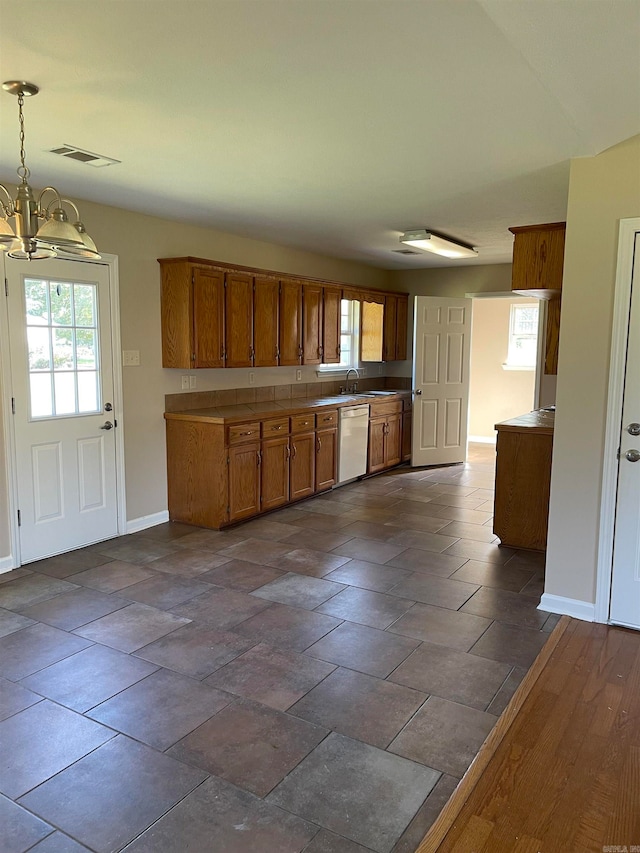 kitchen with an inviting chandelier, decorative light fixtures, white dishwasher, and dark hardwood / wood-style flooring