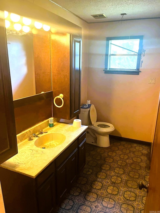 bathroom with vanity, toilet, and a textured ceiling