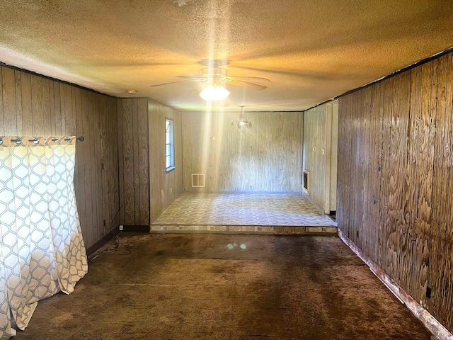 carpeted spare room with ceiling fan, a textured ceiling, and wooden walls