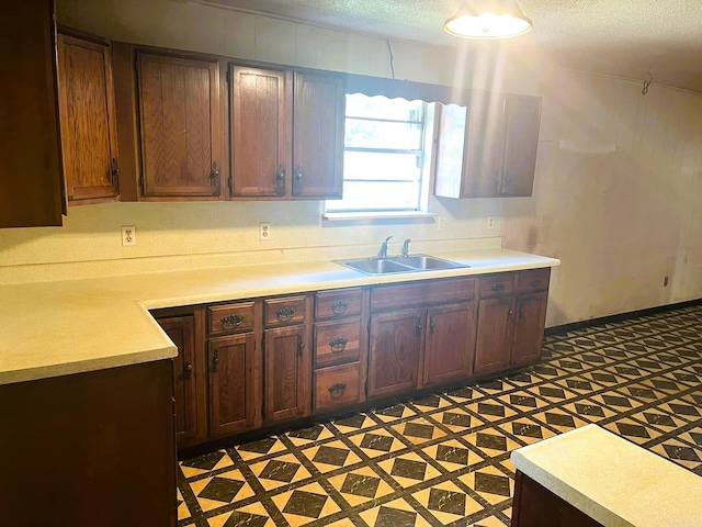 kitchen with dark brown cabinets, a textured ceiling, and sink