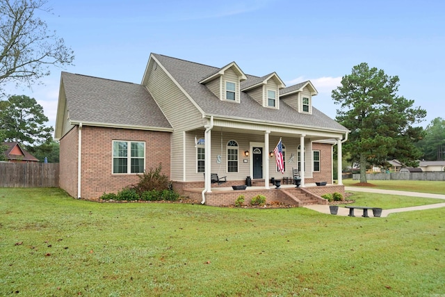 cape cod home with a front yard and a porch