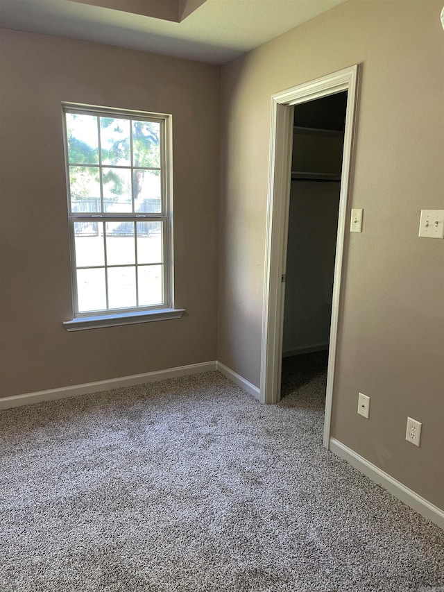 unfurnished bedroom with a closet, carpet, and a spacious closet