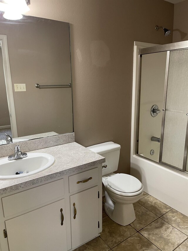 full bathroom with vanity, tile patterned floors, toilet, and combined bath / shower with glass door