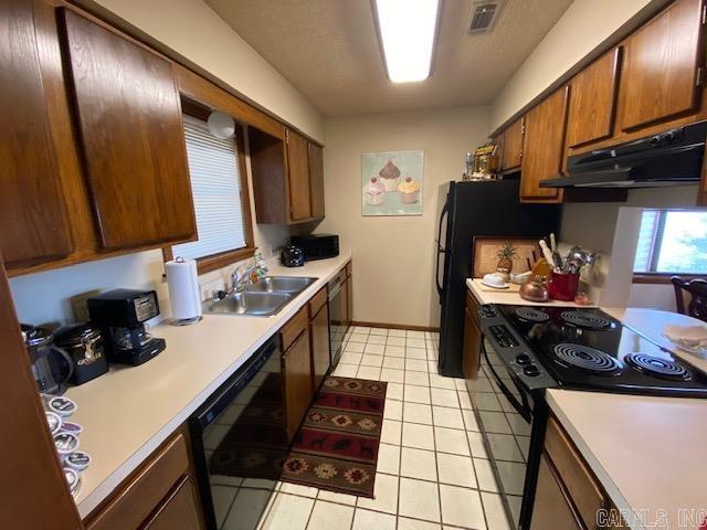 kitchen with light tile patterned floors, sink, and black appliances