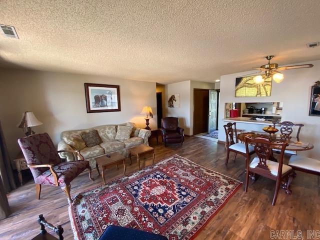 living room featuring ceiling fan, dark hardwood / wood-style flooring, and a textured ceiling