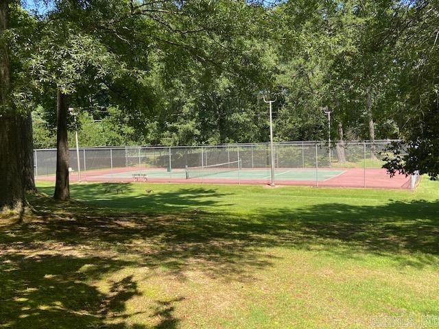 view of tennis court featuring a yard