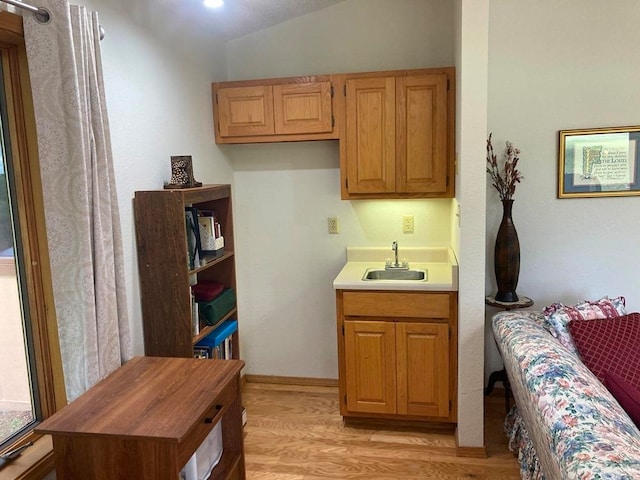 kitchen featuring vaulted ceiling, light wood-type flooring, and sink