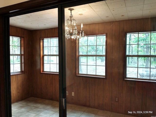 spare room with light tile patterned flooring, wooden walls, and a chandelier