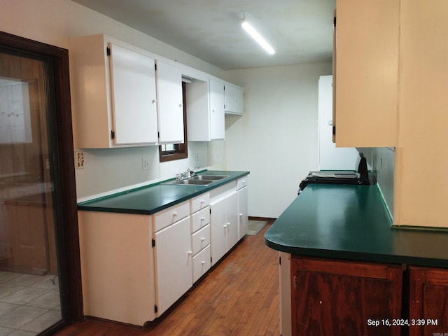 kitchen featuring wood-type flooring, sink, range, and white cabinetry