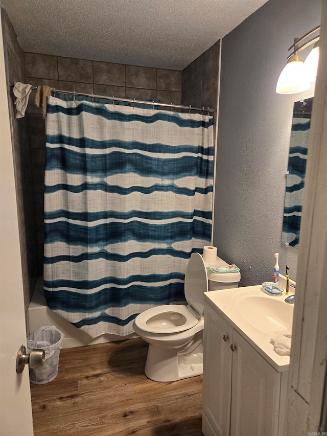 full bathroom with shower / bath combination with curtain, a textured ceiling, hardwood / wood-style flooring, vanity, and toilet