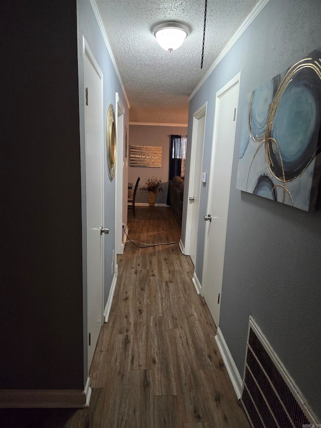 hallway with a textured ceiling, crown molding, and hardwood / wood-style floors