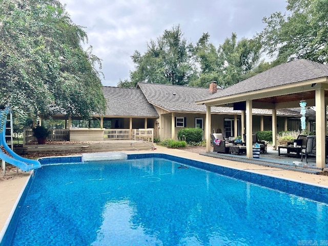 view of swimming pool with a patio, an outdoor living space, and a water slide