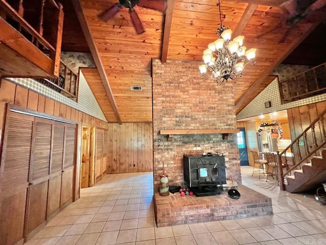 unfurnished living room featuring high vaulted ceiling, ceiling fan with notable chandelier, a fireplace, wooden ceiling, and wooden walls