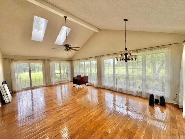 unfurnished living room with a skylight, beam ceiling, wood-type flooring, a textured ceiling, and ceiling fan with notable chandelier