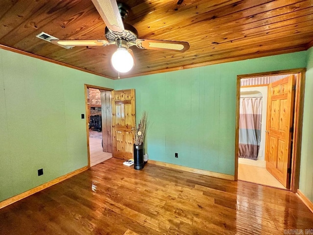 empty room with ceiling fan, crown molding, hardwood / wood-style floors, and wooden ceiling