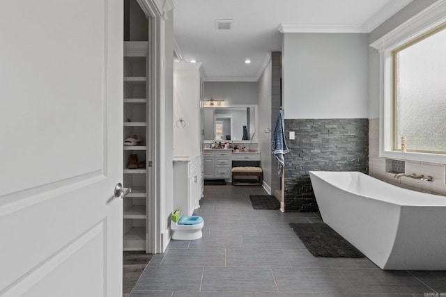 bathroom featuring vanity, a bathing tub, ornamental molding, and a healthy amount of sunlight