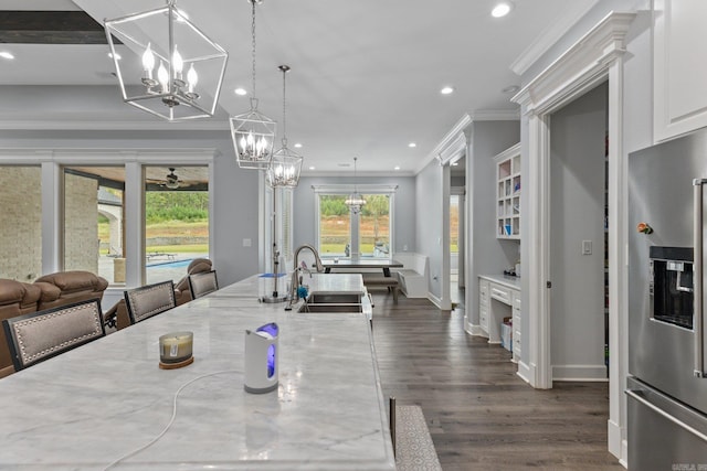 dining room with ceiling fan with notable chandelier, crown molding, dark wood-type flooring, and sink