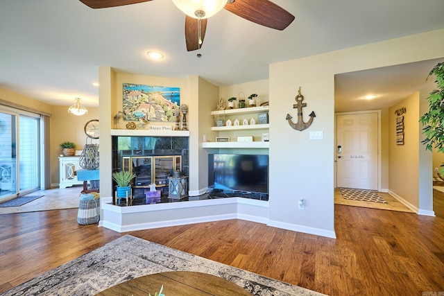 unfurnished living room with ceiling fan, a tile fireplace, and hardwood / wood-style floors