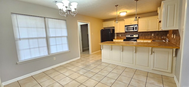 kitchen with hanging light fixtures, decorative backsplash, kitchen peninsula, stainless steel appliances, and an inviting chandelier