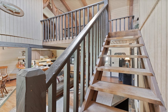 staircase featuring a towering ceiling, wood walls, and hardwood / wood-style floors