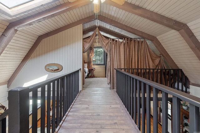 interior space featuring wood-type flooring, vaulted ceiling with skylight, wooden ceiling, and wooden walls