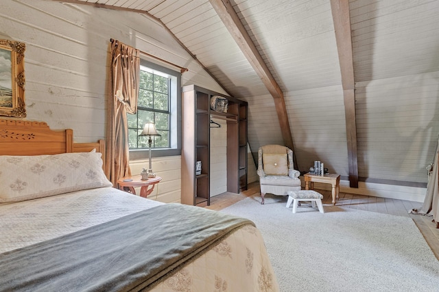 bedroom featuring lofted ceiling with beams, wood ceiling, a closet, light hardwood / wood-style flooring, and wooden walls