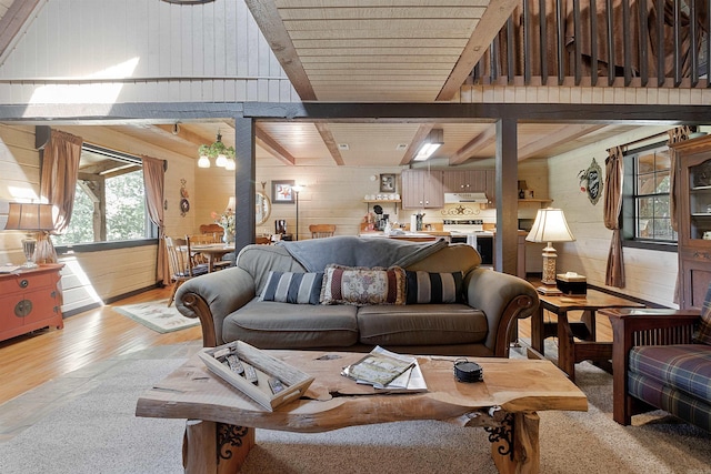 living room featuring vaulted ceiling with beams, wood walls, and light hardwood / wood-style flooring