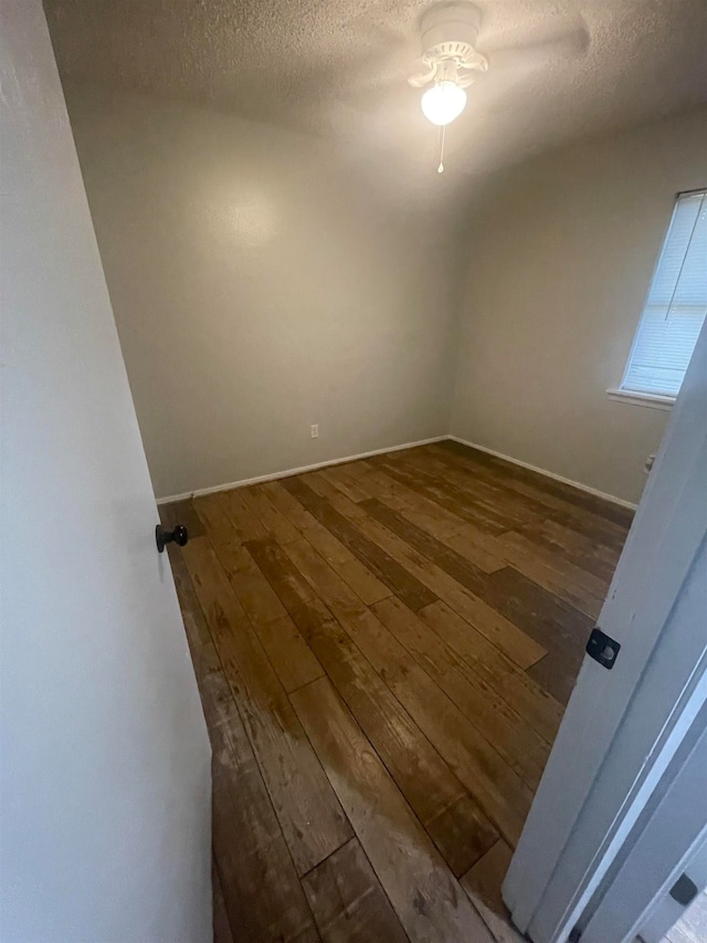 spare room with a textured ceiling and dark hardwood / wood-style flooring