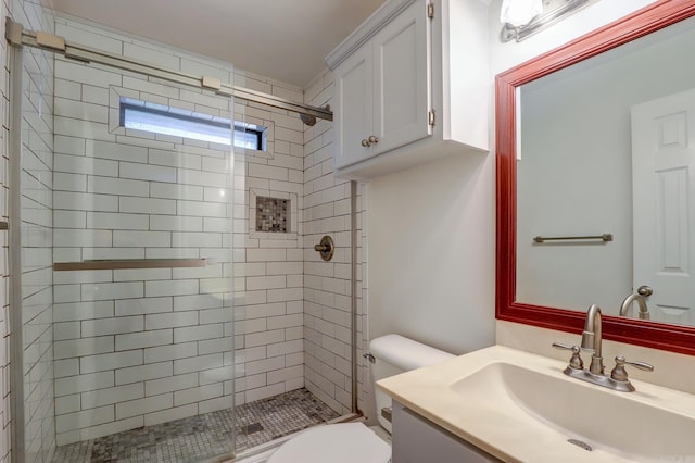 bathroom with a shower with shower door, vanity, and toilet