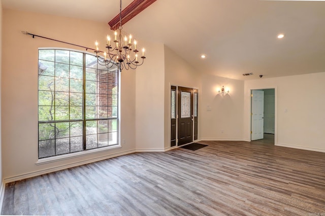 empty room featuring lofted ceiling with beams, wood-type flooring, and a chandelier