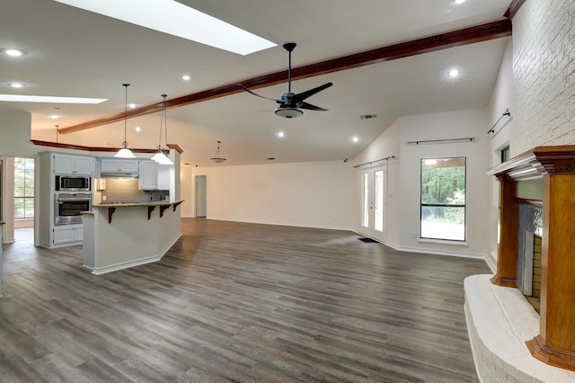 unfurnished living room featuring a healthy amount of sunlight, dark wood-type flooring, and ceiling fan